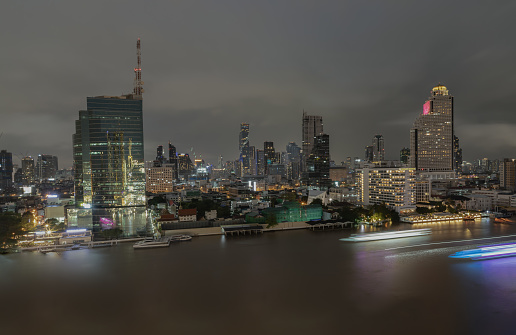 Bangkok, thailand - Aug 22, 2022 : Skyscrapers in the business district along chaopraya river of Bangkok city at night under Sprinkling rain. Rainy season, No focus, specifically.