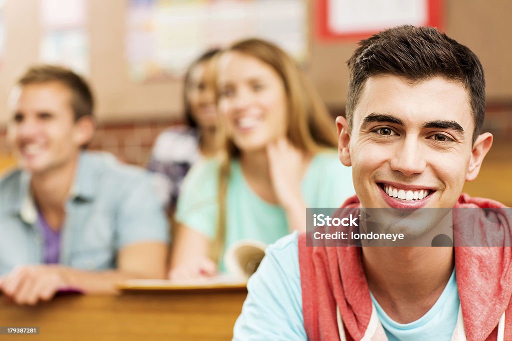 Mężczyzna student uśmiech z uczniów w tle w Sala wykładowa - Zbiór zdjęć royalty-free (16-17 lat)