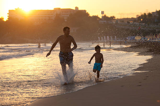 Father and son on the beach at sunset stock photo