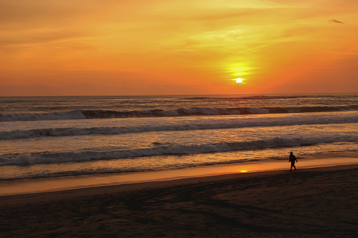 Fulll frame shot of one unrecognizable person walking in empty Bali beach during sunset