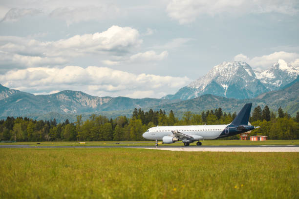 Commercial airplane moving towards a runway at the airport. Beautiful Alps in the background.