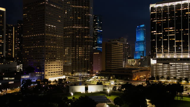 Night Bayfront Park filming location stands against illuminated skyscrapers in Downtown Miami, Florida. Aerial footage with forward camera motion