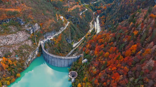 AERIAL Drone Shot of Amazing Turquoise Lake and Dam Along Mountains in Autumn
