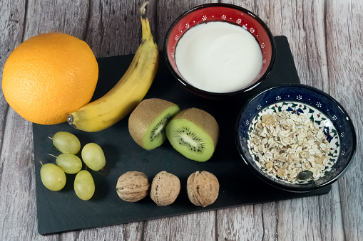 Breakfast rich in vitamins: orange, banana, kiwi, grapes, walnuts with yogurt and cereal