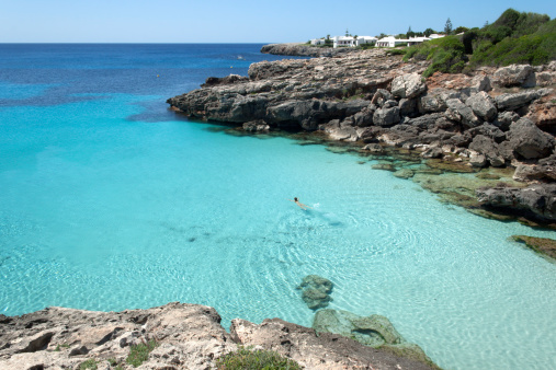 Person swims in an idyllic and transparent sea. Menorca (Balearic Islands, Spain).