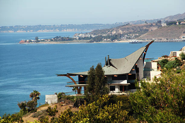 Aerial view of the iconic red-roofed Laguna Cliffs Marriott Resort & Spa overlooking Dana Point, California. Surrounded by coastal hills and residential neighborhoods, the scene is bathed in warm golden light during sunset.