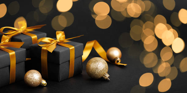 istock Black gift box with golden ribbon bow on black background 1794056545