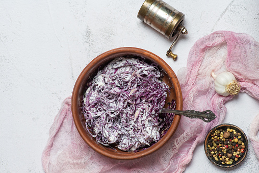 Fresh salad with chopped red cabbage and sour cream in a bowl on a light background. With pepper and garlic. Vegetarian, slimming, diet food concept
