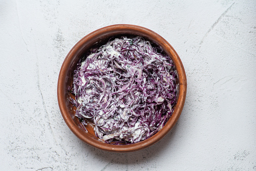 Fresh salad with chopped red cabbage and sour cream in a bowl on a light background. Vegetarian, slimming, diet food concept