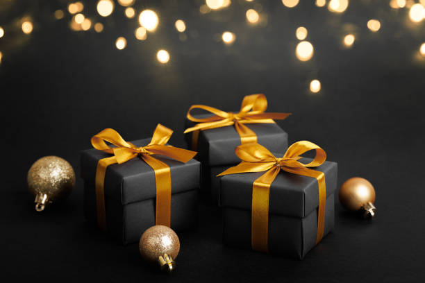 istock Black gift box with golden ribbon bow on black background 1794089092