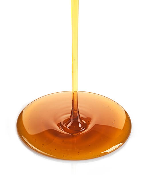 Maple syrup being poured onto white Maple syrup on a white background maple syrup stock pictures, royalty-free photos & images