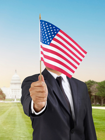 Businessman holding a USA  flag in front of Capitol building in Washington DC