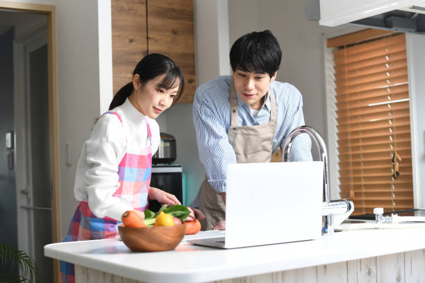 istock Asian couple cooking while checking recipes on laptop in their home kitchen 1794135968