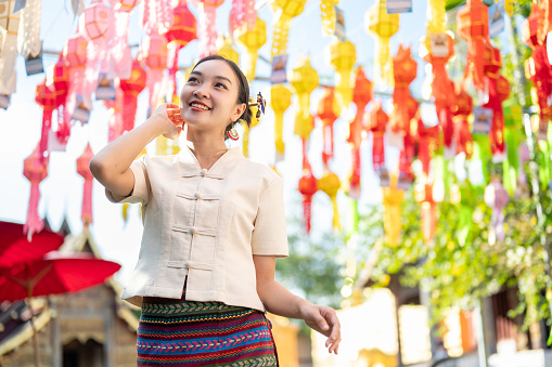 A beautiful and happy young Asian-Thai woman in a traditional Thai-Lanna dress is enjoying in a Thai-Lanna lantern festival or Yi Peng at a temple in Chiang mai. Lanna Loy Krathong festival
