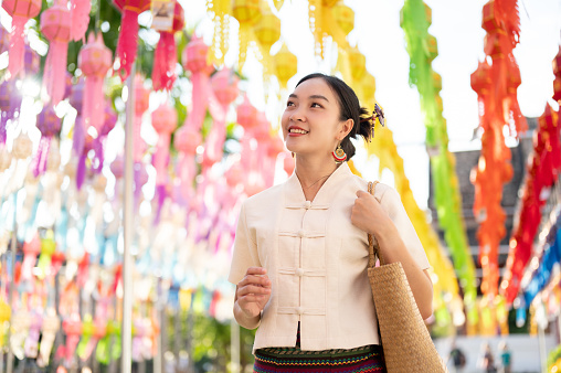 A beautiful and happy young Asian-Thai woman in a traditional Thai-Lanna dress is enjoying in a Thai-Lanna lantern festival or Yi Peng at a temple in Chiang mai. Lanna Loy Krathong festival