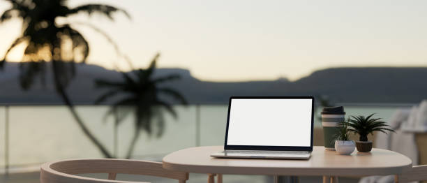 istock A laptop on a table at an outdoors terrace with an ocean view. Holiday, vacation, working remotely 1794154366