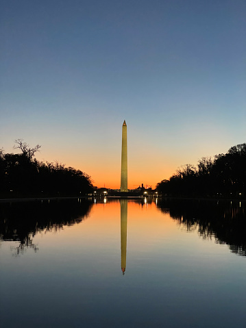 Witness the capital bathed in the golden embrace of a new day with this breathtaking photograph capturing the sunrise behind the iconic Washington Monument. The warm hues of the rising sun paint the sky, casting a serene glow upon the majestic silhouette of the monument. This evocative image perfectly encapsulates the symbolic and historic significance of Washington D.C. Ideal for adding a touch of patriotism and awe-inspiring beauty to your creative projects. Illuminate your designs with the timeless elegance of a Washington sunrise.