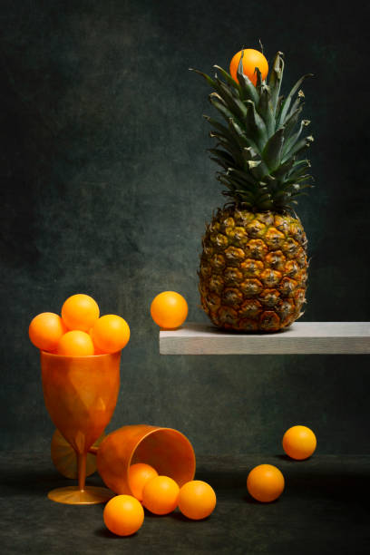 Still life with pineapple and orange balls in a glass