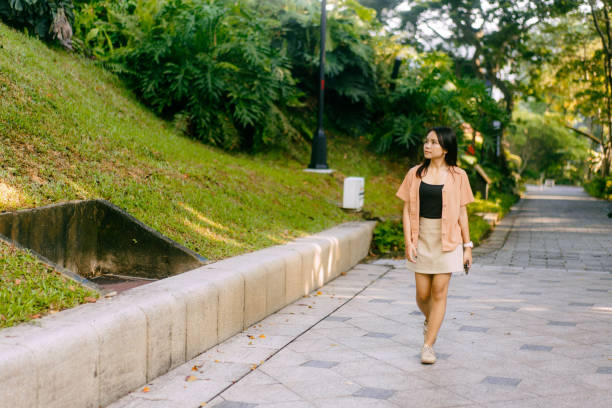 Asian Girl Strolling Lush Green Public Park stock photo