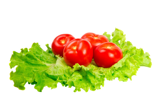 tomatoes on lettuce leaves on a white background