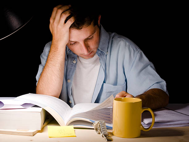 Student studying at night with a desk lamp on stock photo