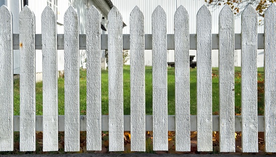 fence of a white wooden garden front view with green grass and part of house background