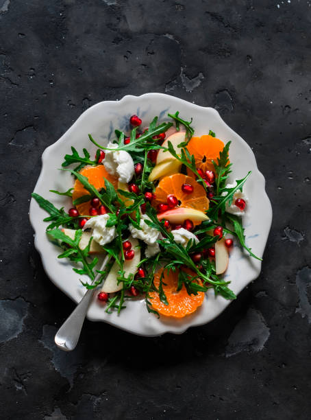 istock Rocket salad with tangerines, pomegranate, apples and mozzarella cheese on a dark background, top view 1794265213