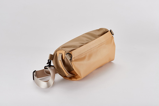 a brown sling bag with a white background