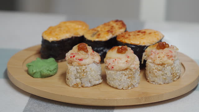 woman eating sushi, set of different rolls sushi on wooden plate, japanese cuisine close-up