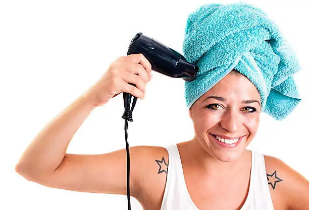 Happy girl hairdrying. She has a hair dryer in the hand and a towel in her head.