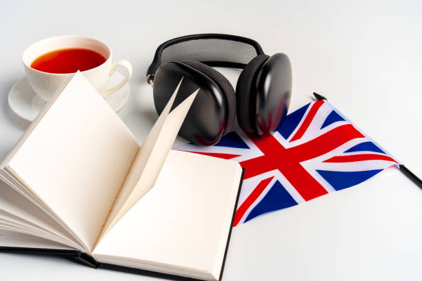 blocco note con bandiera britannica e cuffie su sfondo bianco. concetto educativo di audiocorsi in lingua inglese - british culture audio foto e immagini stock