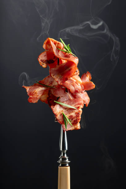 istock Roasted bacon slices with rosemary on a fork. 1794329304