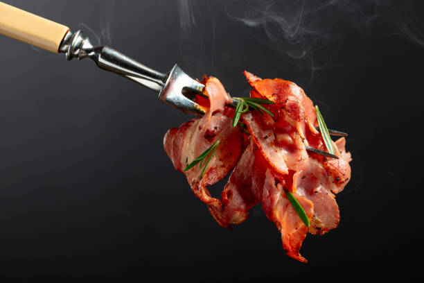 istock Hot fried bacon slices with rosemary on a fork. 1794329789