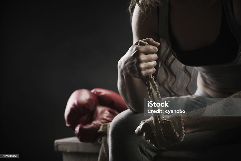 Woman boxer wrapping bandage around hand prior to game Woman boxer wearing white strap on wrist Boxing - Sport Stock Photo