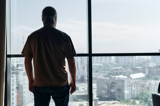istock Man looking out the window at the city 1794342686