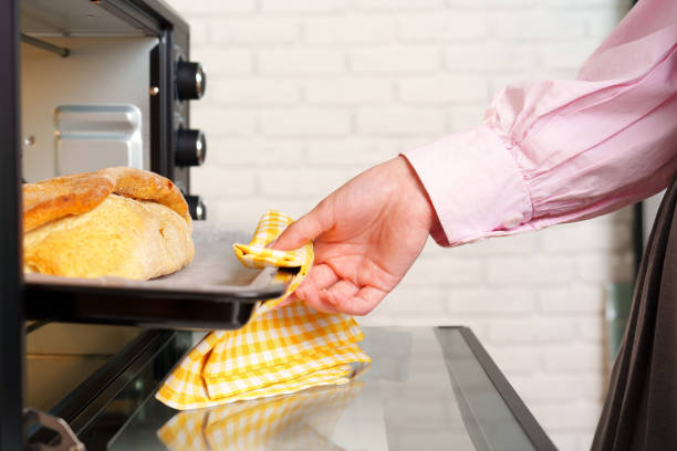 istock Woman's hands taking fresh bakery out of mini oven 1794343763