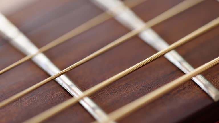 Closeup of wooden guitar strings 4k movie slow motion