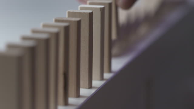 male hand puts wooden domino blocks in a line, domino effect slow motion