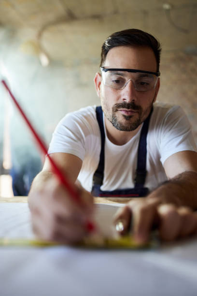 istock Young manual worker drawing measurements at construction site. 1794420517