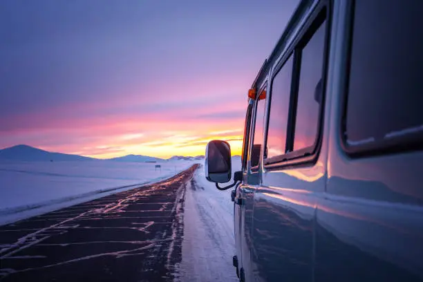 Photo of A van for traveling in winter when the roads are covered with snow during twilight.