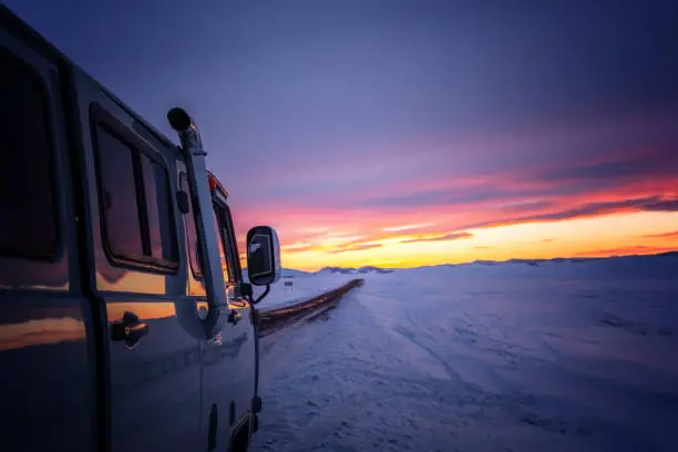 Photo of A van for traveling in winter when the roads are covered with snow during twilight.