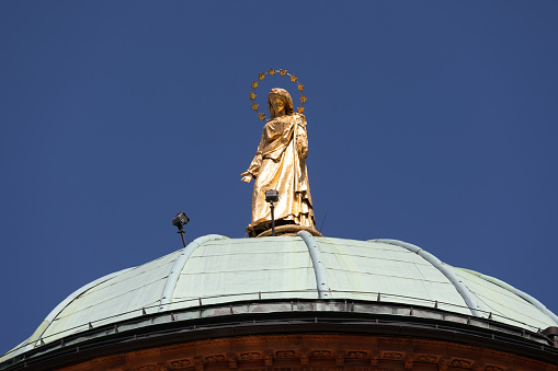 Bergamo, Italy - June 13, 2019: Gold Statue at Top of Roman Catholic Church Santa Maria delle Grazie in Bergamo, Italy.