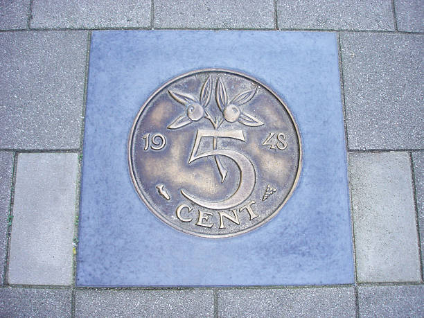 Coin of five Dutch cents in pavement Former Dutch five cents coin cemented in sidewalk dutch guilders stock pictures, royalty-free photos & images