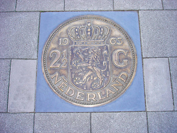 Coin of 2,5 Dutch guilders in pavement Former Dutch coin piece of 2,5 guilders cemented in sidewalk dutch guilders stock pictures, royalty-free photos & images