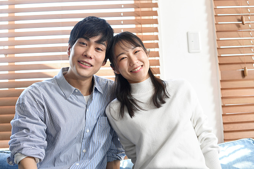 Smiling young Asian man and woman sitting on the sofa