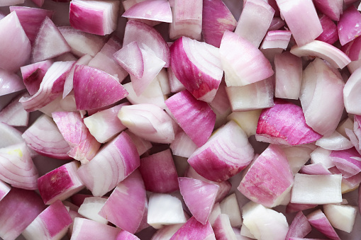 Stock photo showing a close-up, elevated view of healthy eating image of red onion roughly diced. Pieces of vegetables displaying purple skin and white flesh.