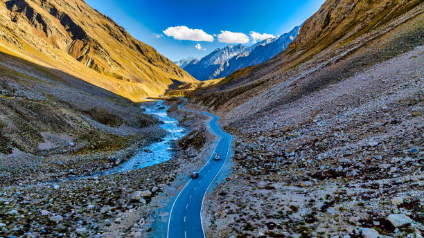 istock Aerial view of a road alongside river stream through mountains 1794513765