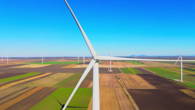 Aerial view of wind turbines on agricultural field on a sunny day with a stunning blue sky and clouds - Stock Video