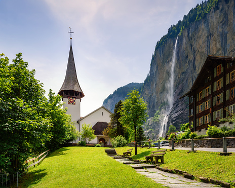 Amazing landscape of touristic alpine village Lauterbrunnen with famous church and Staubbach waterfall. Location: Lauterbrunnen village, Berner Oberland, Switzerland, Europe.