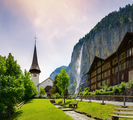 Amazing landscape of touristic alpine village Lauterbrunnen with famous church and Staubbach waterfall. Location: Lauterbrunnen village, Berner Oberland, Switzerland, Europe.